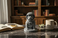 Statue of a dog in an astronaut suit on a shelf with books and a camera.