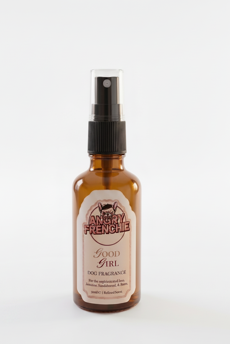 An amber glass spray bottle with a black pump dispenser and a cream-colored label that reads 'Angry Freeshie Good Girl' on a clean white background.
